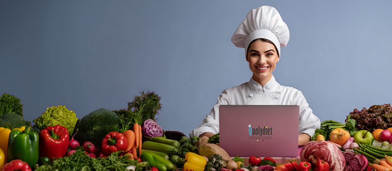 Cheffe devant un ordinateur portable Mac apprenant les techniques culinaires avec autour d'elle des légumes